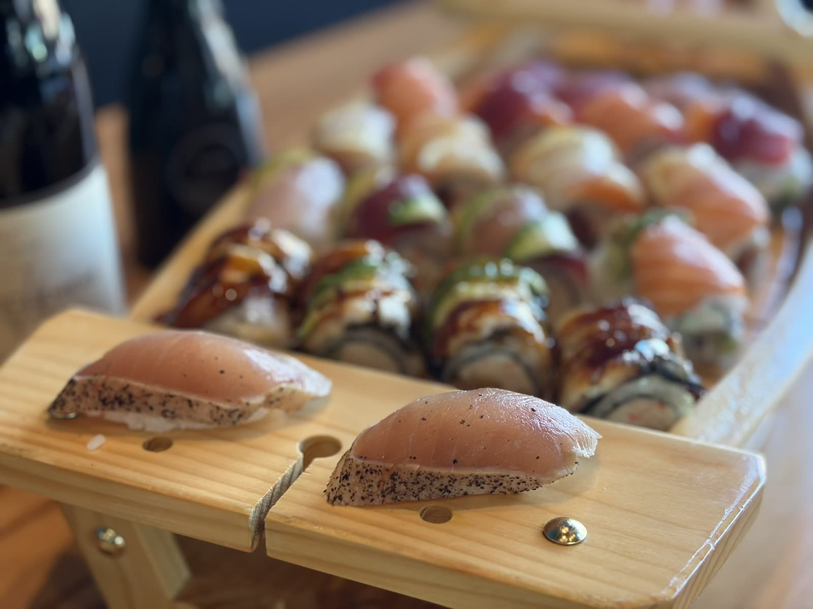 Seared nigiri on a wooden sushi boat with assorted rolls